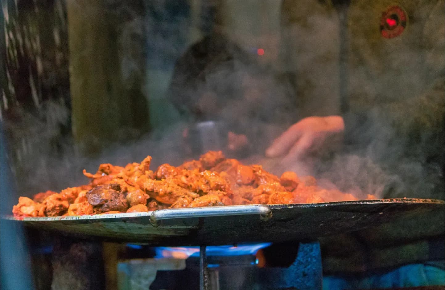 Large plate of chicken being cooked over a open fire